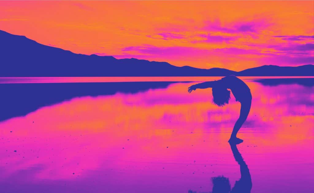 Woman arching backward on a beach at sunset, reflecting intuitive energy and stillness